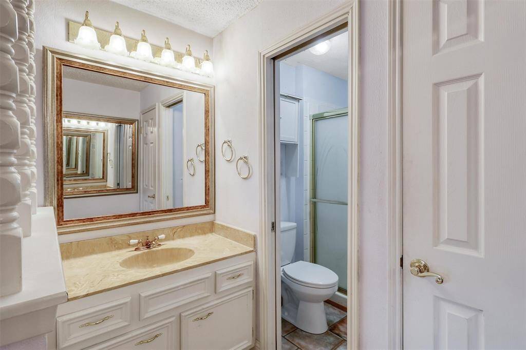 This photo showcases a compact bathroom with a light-colored vanity, a large mirror, and overhead lighting. It features a toilet and a shower with a sliding glass door, creating a functional and cozy space.
