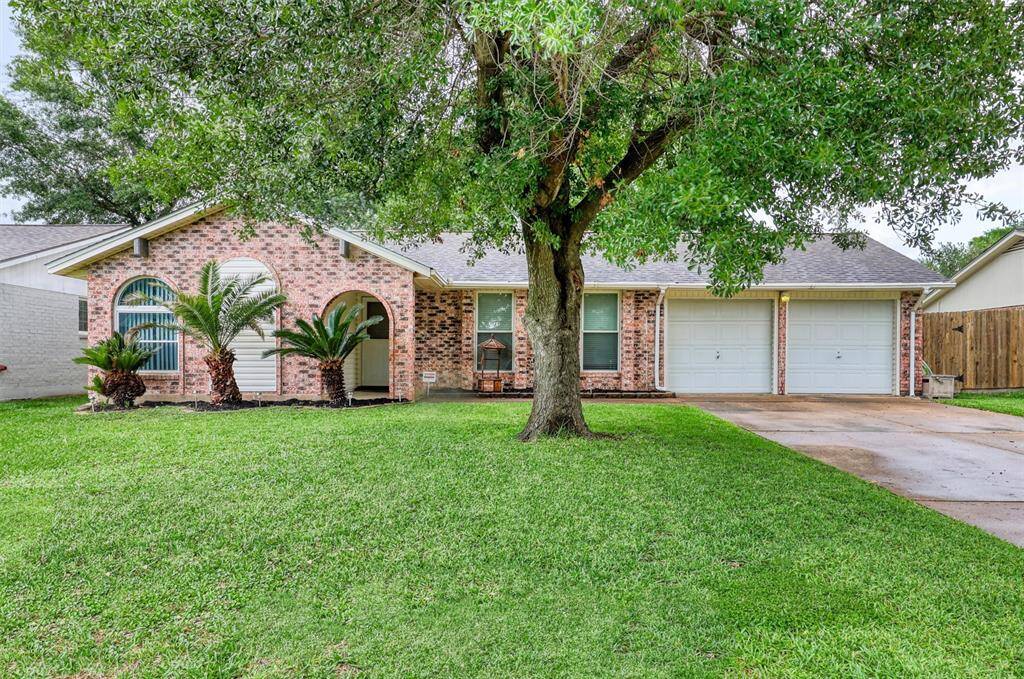 Charming brick home with a manicured lawn and mature tree in the front yard. Features include a welcoming archway, two-car garage, and stylish arched windows. Ideal for comfortable living.