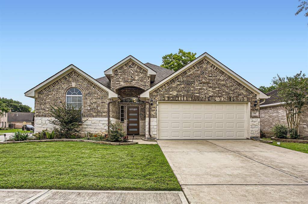 Charming single-story brick home featuring a two-car garage and a welcoming front yard with well-maintained landscaping. The arched window and clean driveway add to its curb appeal.