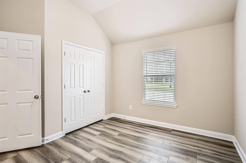 This bedroom features neutral walls, wood flooring, a double closet, offering a bright and versatile space.