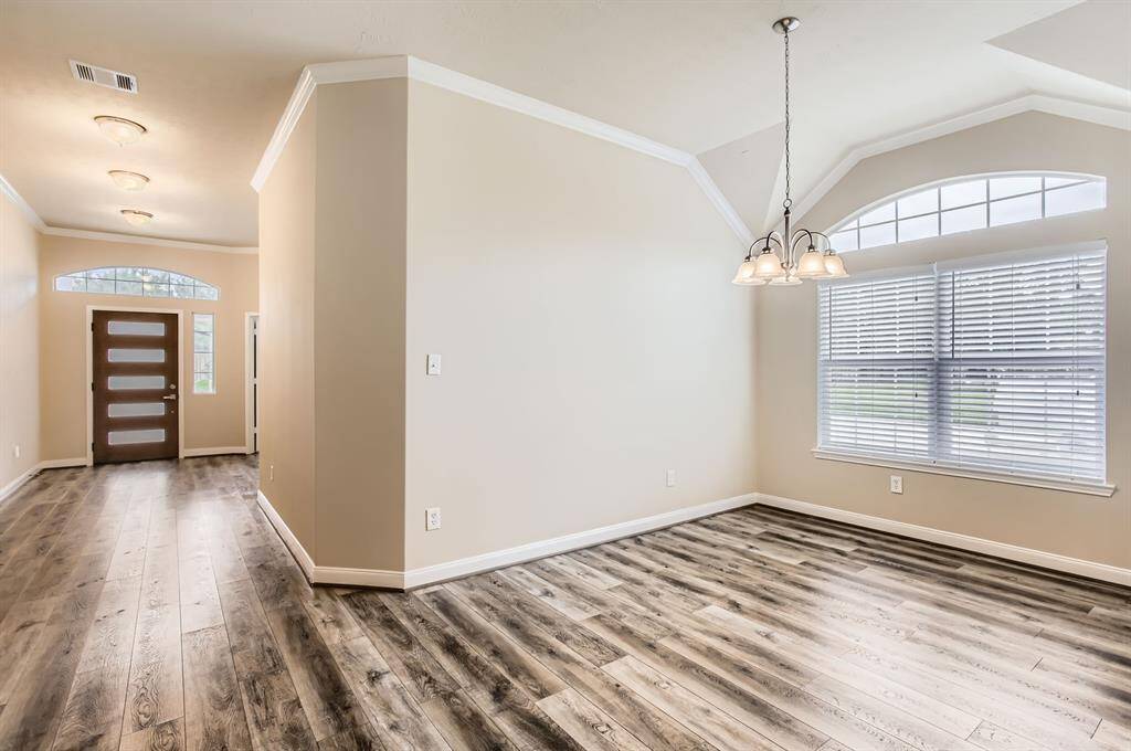 View of front entry, bright and inviting entryway leading to a dining area. The space features wood flooring, neutral walls, and large windows for ample natural light. A modern chandelier adds a touch of sophistication.
