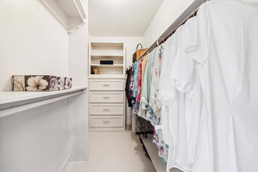 Walk-in closet features built-in shelves, drawers and clothes hanging rods.