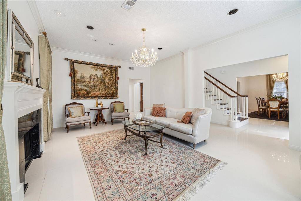 Spacious living room has sparkling chandelier, gas log fire place and tile flooring.