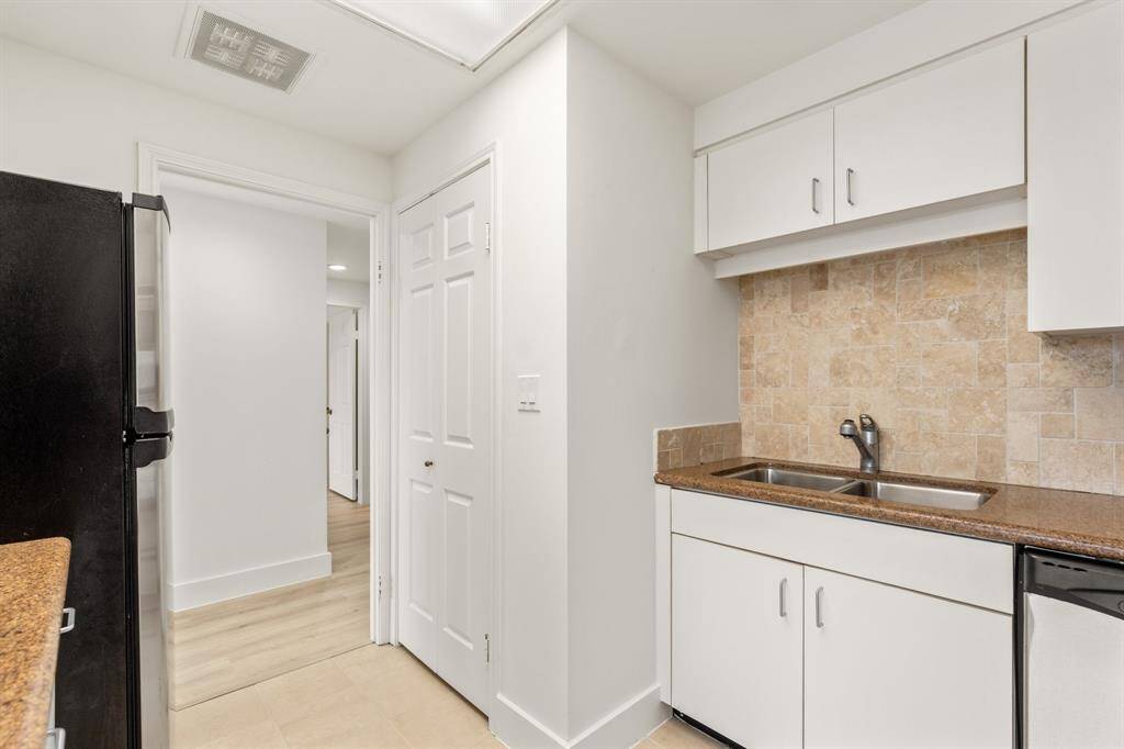 Kitchen with utility closet to left of sink with stacked washer/dryer.