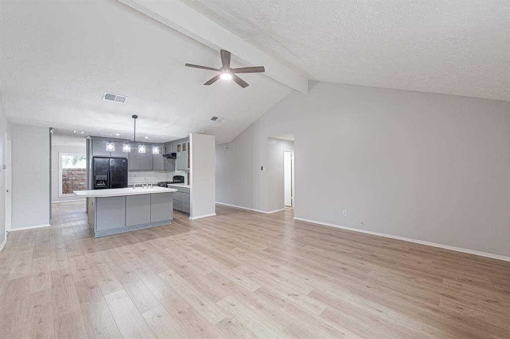 Luxury vinyl plank flooring extends from the front door, through the dining, kitchen and living room.  Ceilings vault to 12' and a wall of windows let natural light flow through the home.  This view highlights the open concept floor plan.