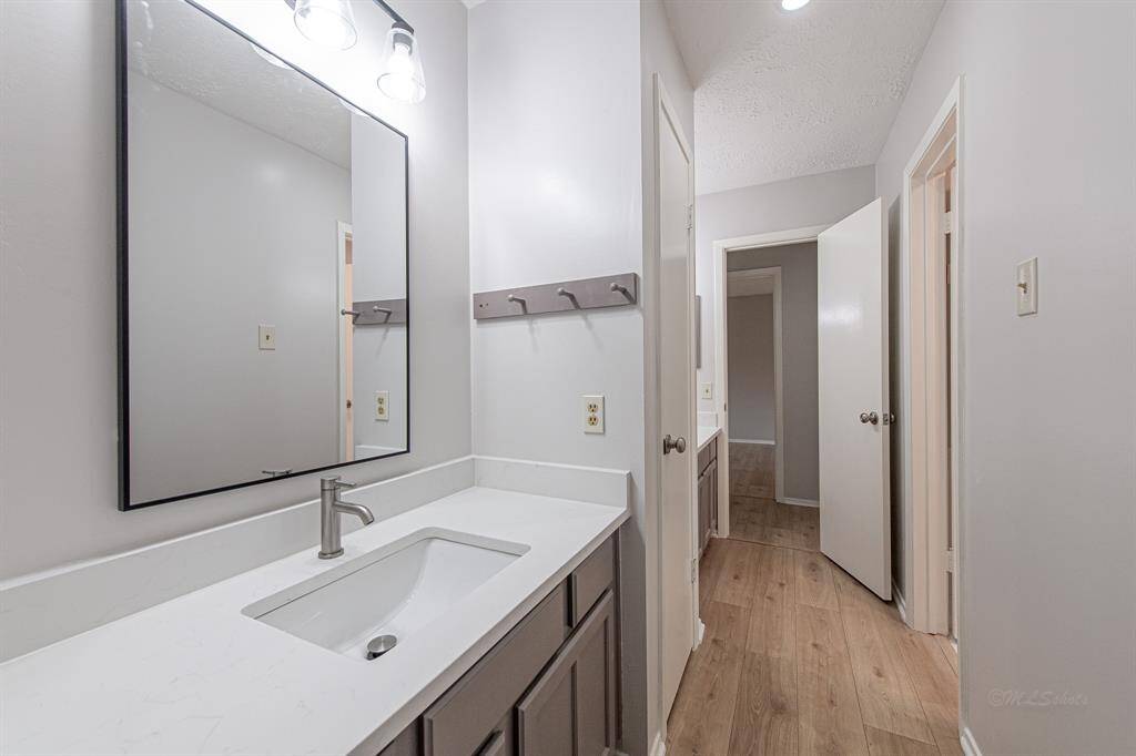 The second vanity features a modern light fixture, quartz counters, freshly painted cabinets, framed mirror, brushed nickel faucet, and medicine cabinet.  Note the luxury vinyl floors that continue through this space.