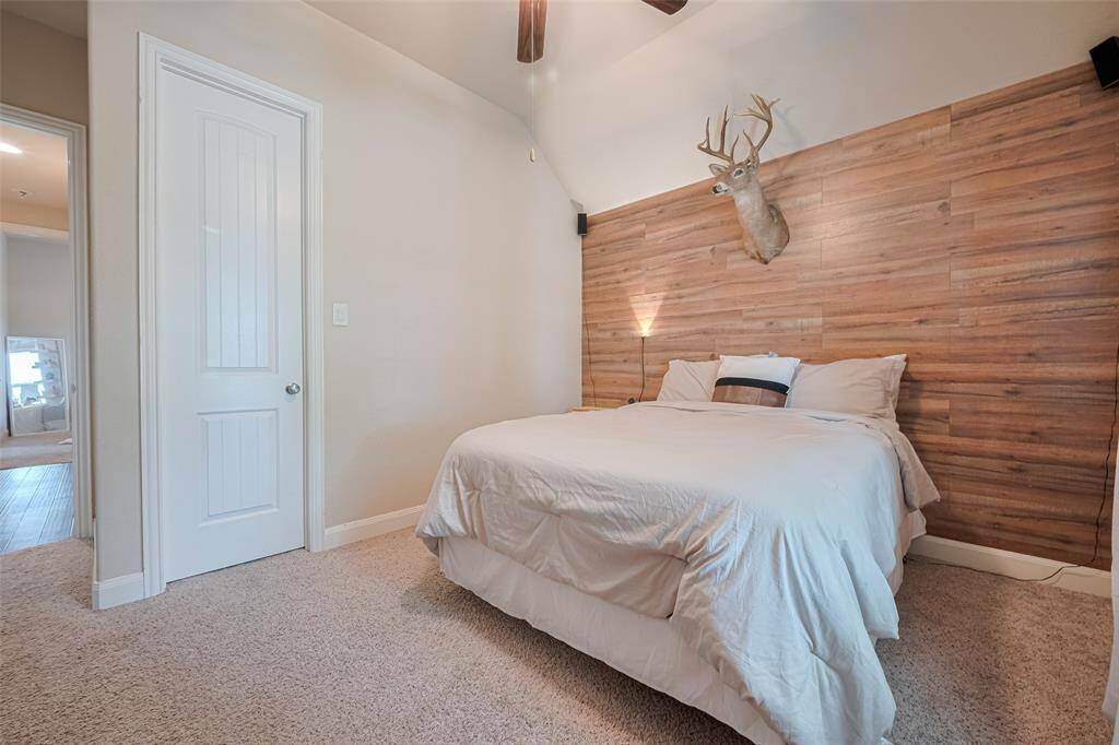 Another well-proportioned room, this bedroom stands out with warm carpeting and a distinctive wood-paneled accent wall, offering both style and comfort.