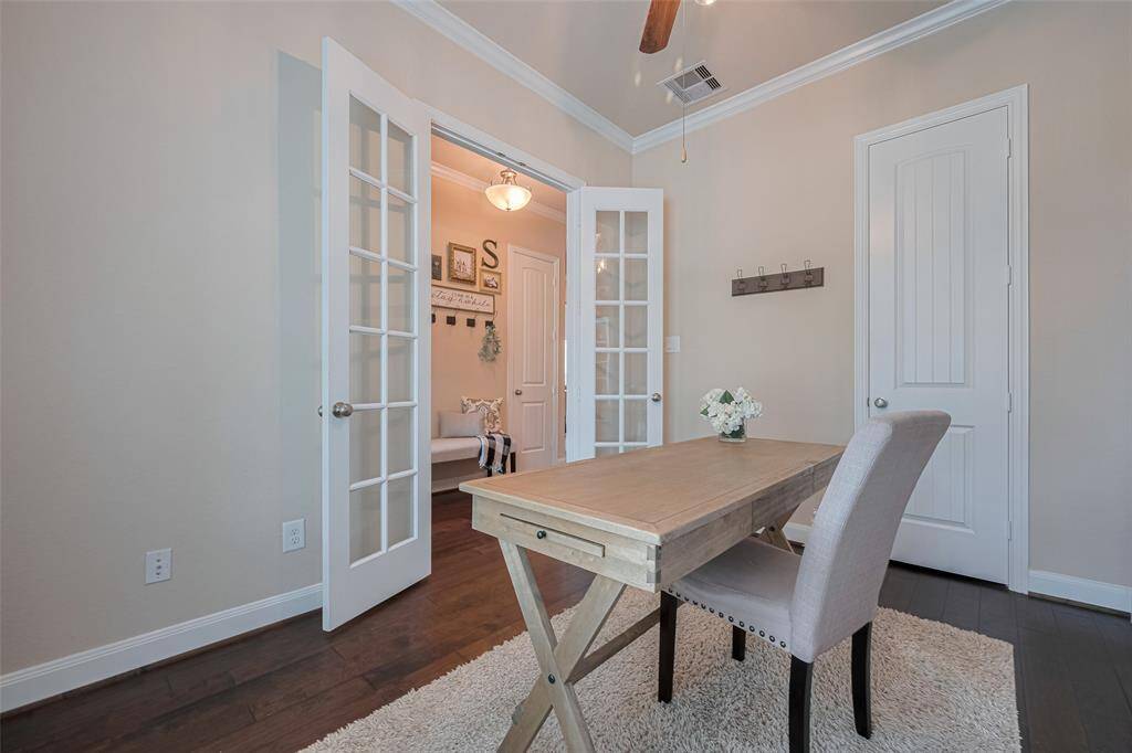 Set behind classic double French doors, this office space features rich-toned flooring that contrasts beautifully with colorful walls. A charming arched window draws in natural light, lending a warm and inviting atmosphere—ideal for working, studying, or unwinding in a quiet retreat.