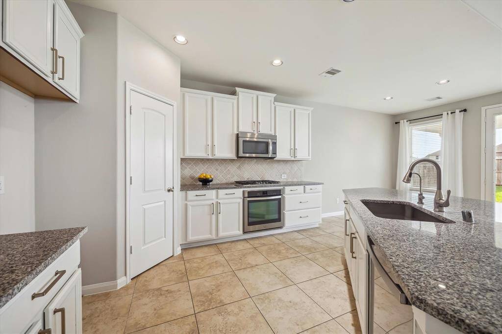 Stainless steel appliances with a gas range and a walk-in pantry round out the highlights of this stylish and functional kitchen.