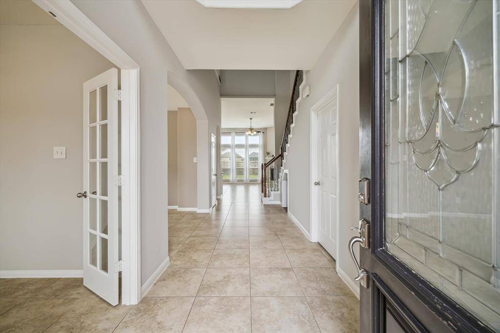 The entry greets you with warm neutral tones, with a peek through to the living space and entry to the dedicated office through double doors.