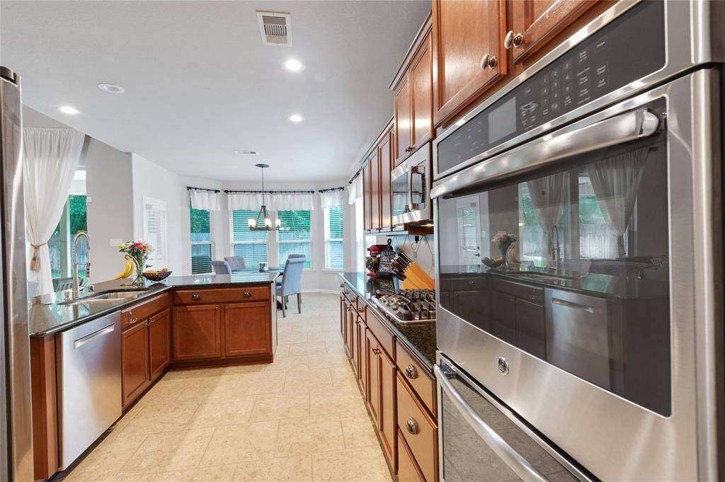 Another view of the large kitchen with double ovens , gas cooktop , and a ton of storage space .