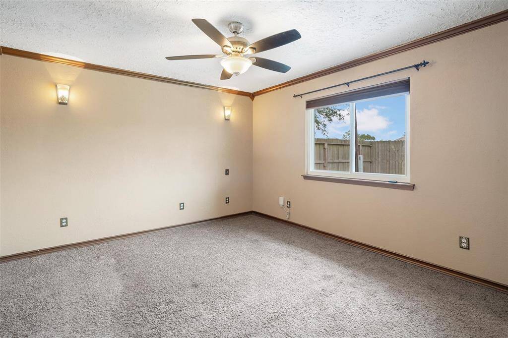 Primary bedroom with sconce lighting plus a ceiling fan