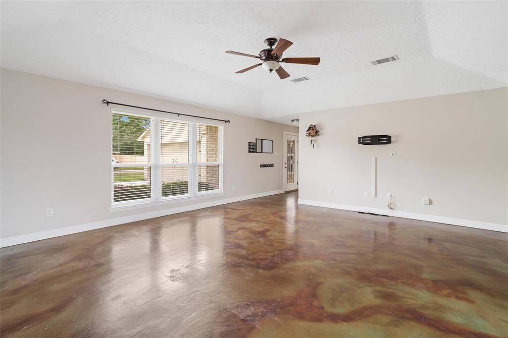 Living room space with picture window letting in natural light, natural concrete floors