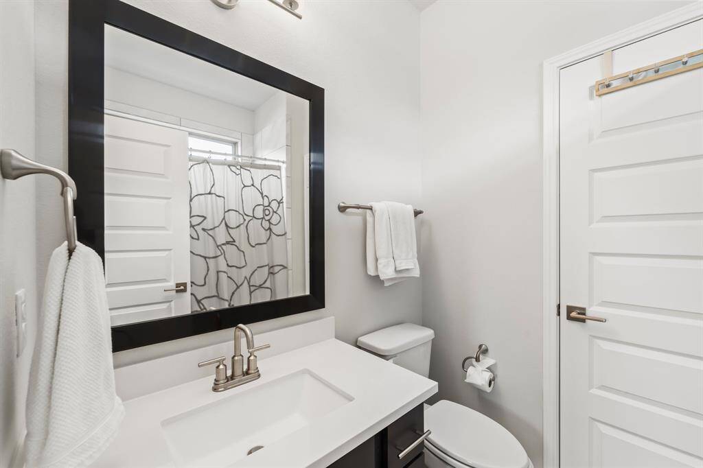 Secondary bedroom #1's bathroom, with tub/shower combo shown in the mirror.