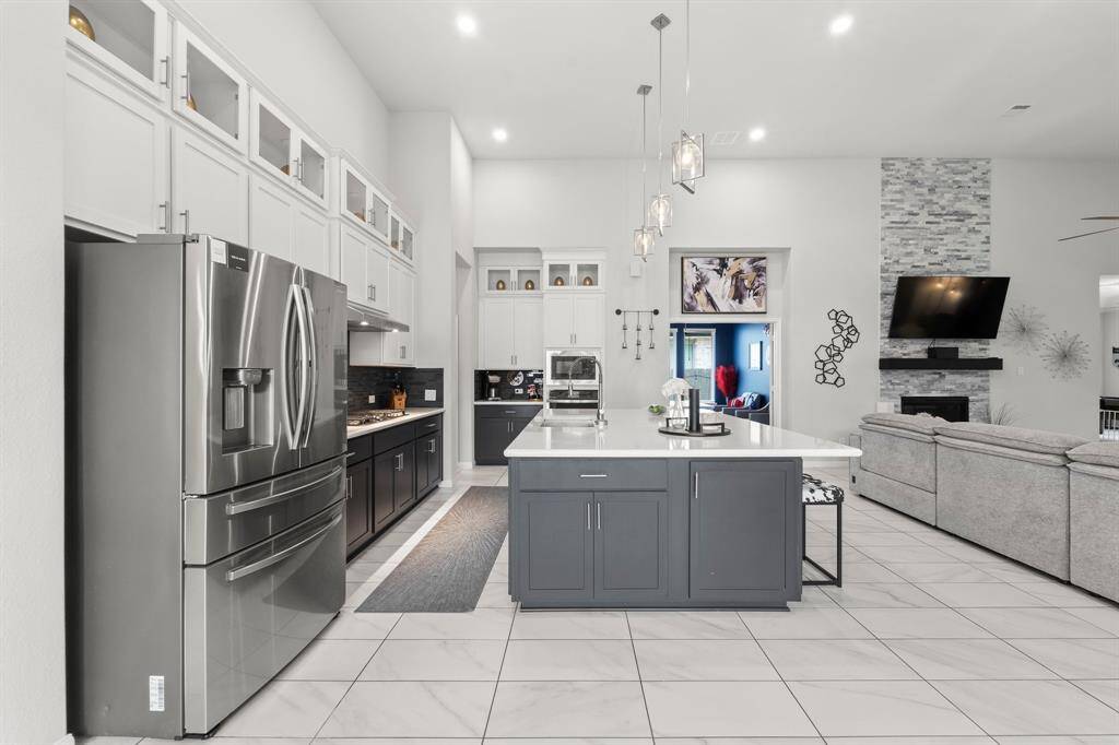 View of this amazing kitchen from the dining room. Two toned cabinets with the grey on the bottom and white on the top adds a different level of custom design to this home.