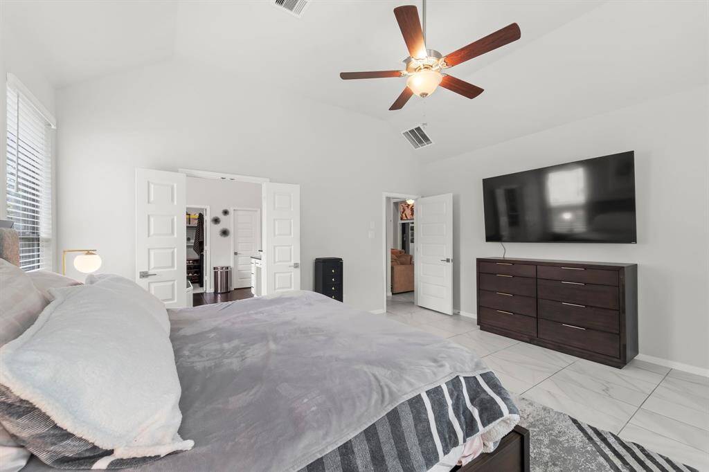 Spacious primary bedroom has high, vaulted ceilings and plenty of room for large furniture.