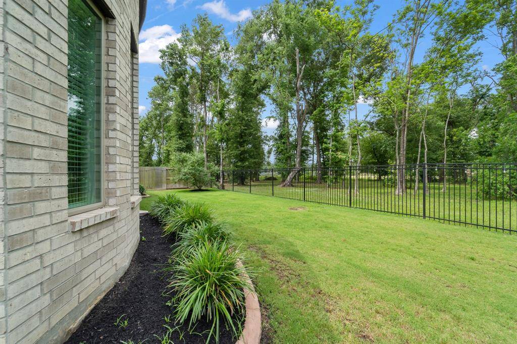 View of the green space behind the home with wrought iron fencing.