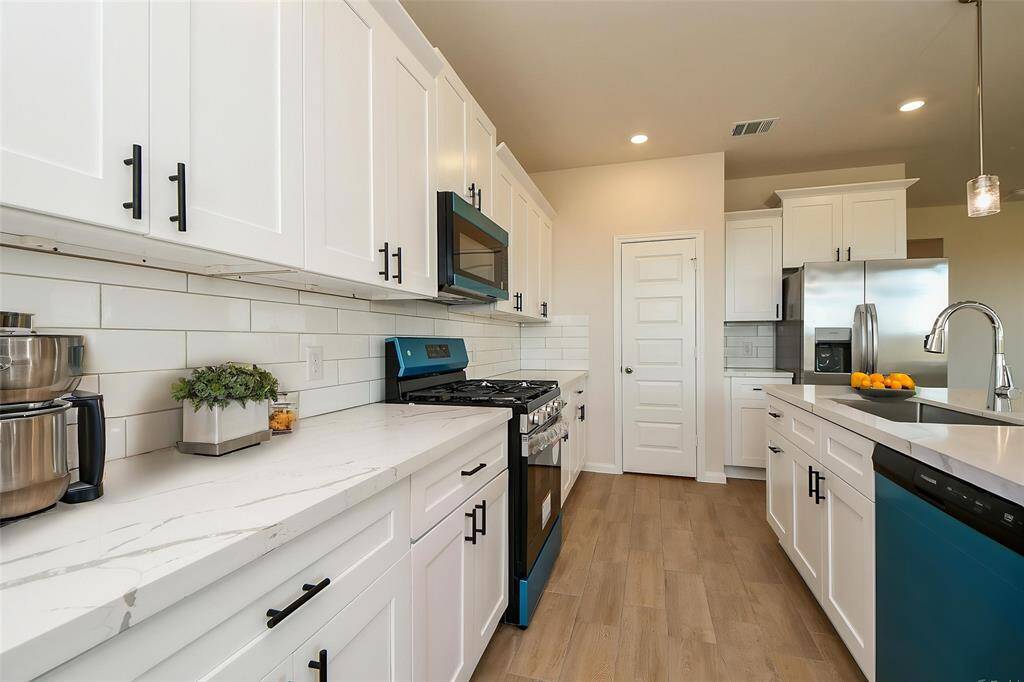 The sleek white cabinetry, complimented by stylish hardware, provides ample storage and a clean contemporary look.