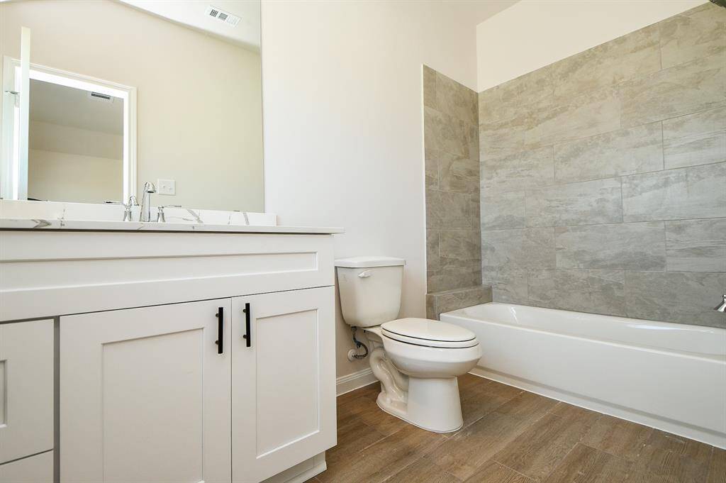 In the bathroom, we have a shower/tub combination with a beautiful grey tiled wall and an expansive countertop.