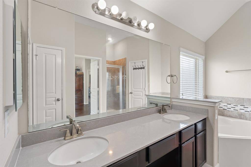 The primary bathroom features a double sink vanity, a large bathtub, and a tiled shower, offering a luxurious and functional space for relaxation and grooming.