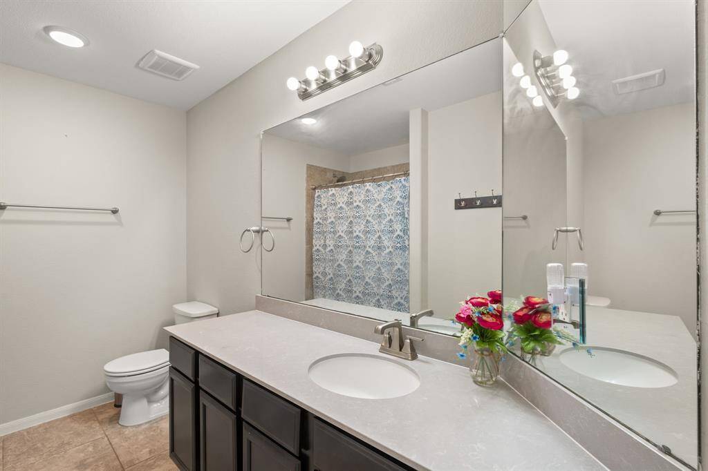 The bathroom boasts a tiled shower/tub combo, a dark stained sink vanity, and tile flooring, creating a stylish and functional space.