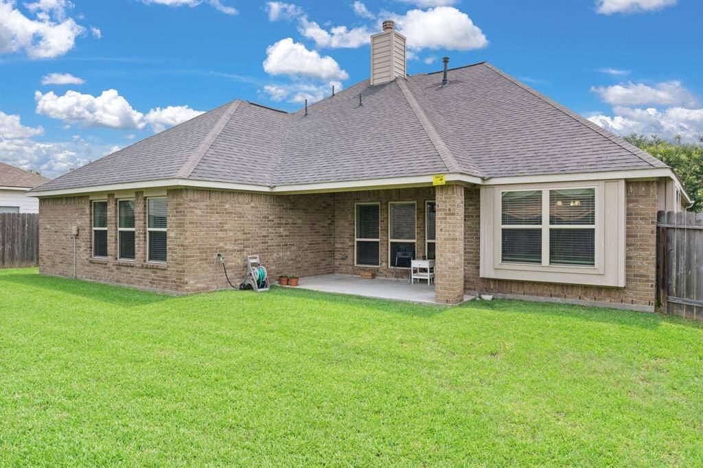 The fenced backyard features a covered patio, offering a private and shaded area perfect for outdoor relaxation and entertainment.