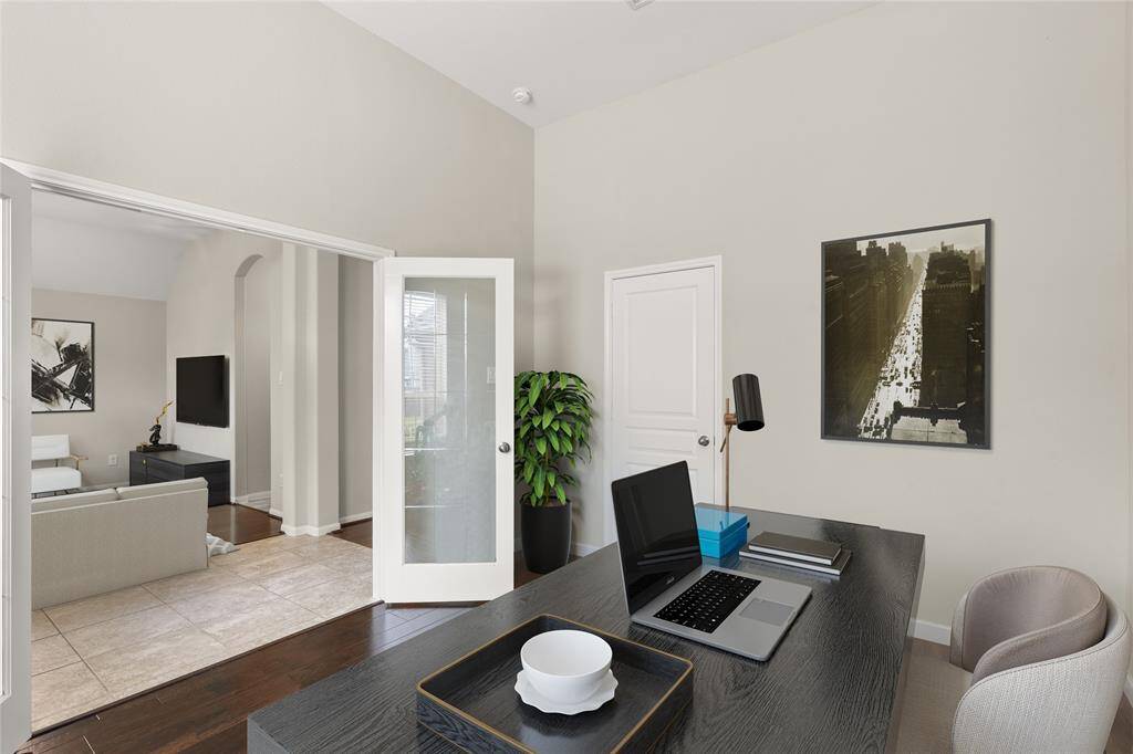 The home office features high ceilings, a window that invites natural light, and sleek laminate flooring, creating an airy and modern workspace.