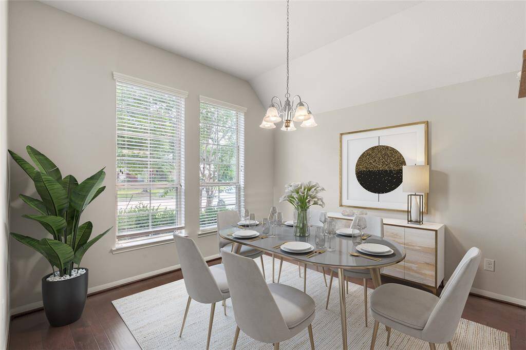 The formal dining room, adorned with vaulted ceilings, two large windows, and an elegant chandelier, offers a spacious and light-filled setting for sophisticated meals and gatherings.