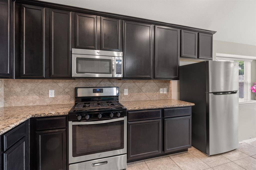 The kitchen showcases granite countertops, tile backsplash and stainless steel appliances, seamlessly blending elegance with modern functionality.