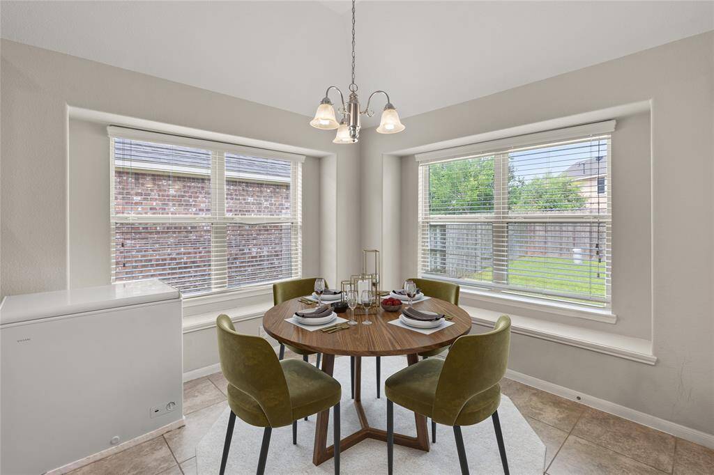 The breakfast area, adorned with windows, a chandelier, and tile flooring, offers a charming and luminous space for enjoying morning meals with a touch of elegance.