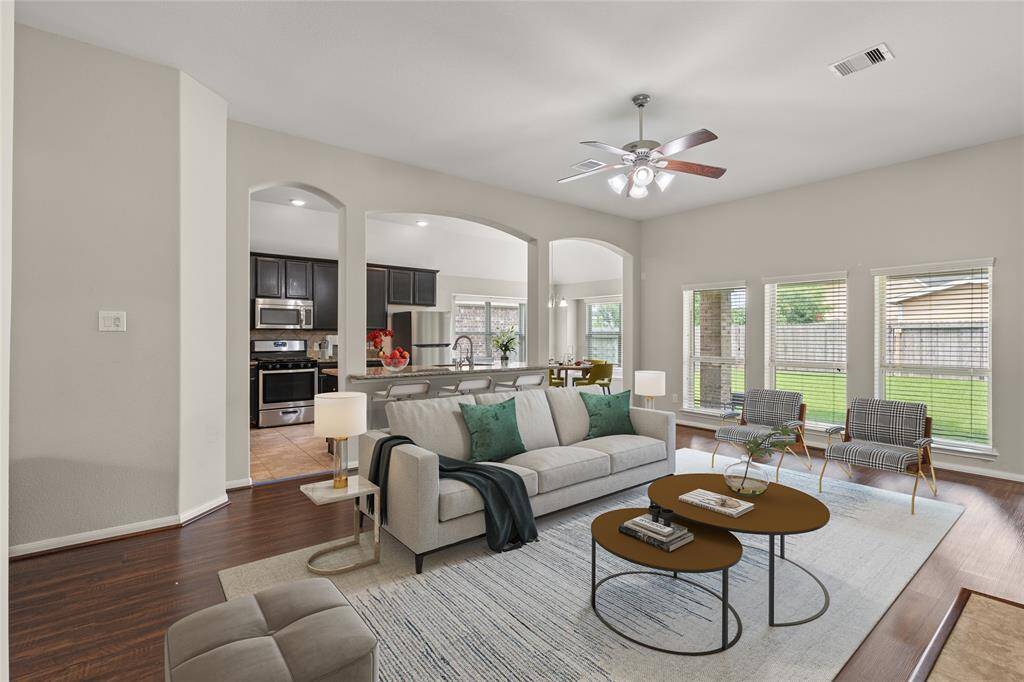 The living room, open to the kitchen, features three large windows that fill the space with natural light, creating a seamless and airy environment for both relaxation and culinary activities.