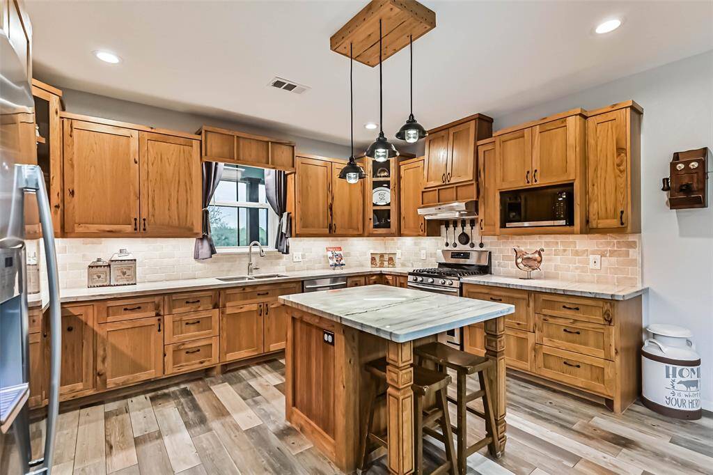 Chef's eat-in island kitchen features custom hickory cabinets, designer backsplash, lengthy countertops, stainless steel appliances and under cabinet lighting