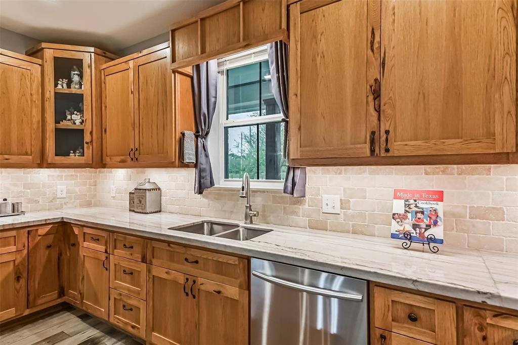 Chef's eat-in island kitchen features custom hickory cabinets, designer backsplash, lengthy countertops, stainless steel appliances and under cabinet lighting
