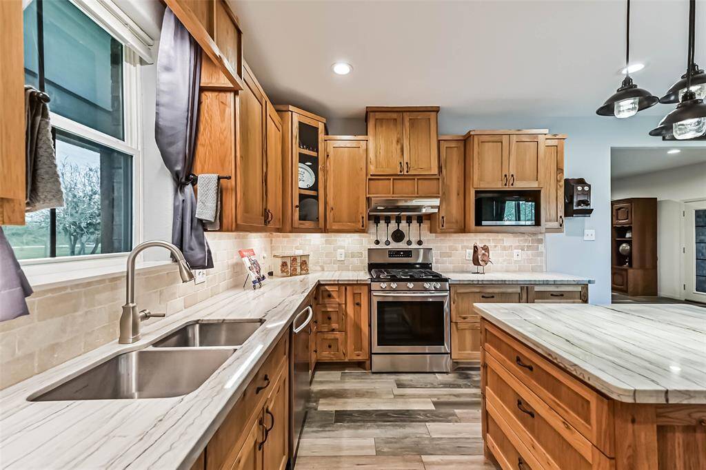Chef's eat-in island kitchen features custom hickory cabinets, designer backsplash, lengthy countertops, stainless steel appliances and under cabinet lighting