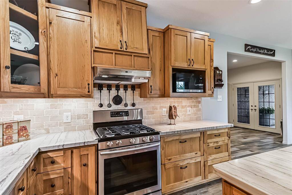 Chef's eat-in island kitchen features custom hickory cabinets, designer backsplash, lengthy countertops, stainless steel appliances and under cabinet lighting