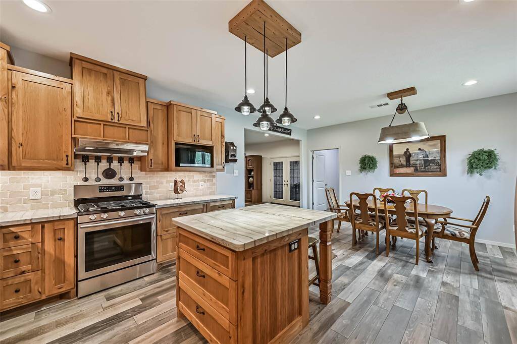 Chef's eat-in island kitchen features custom hickory cabinets, designer backsplash, lengthy countertops, stainless steel appliances and under cabinet lighting