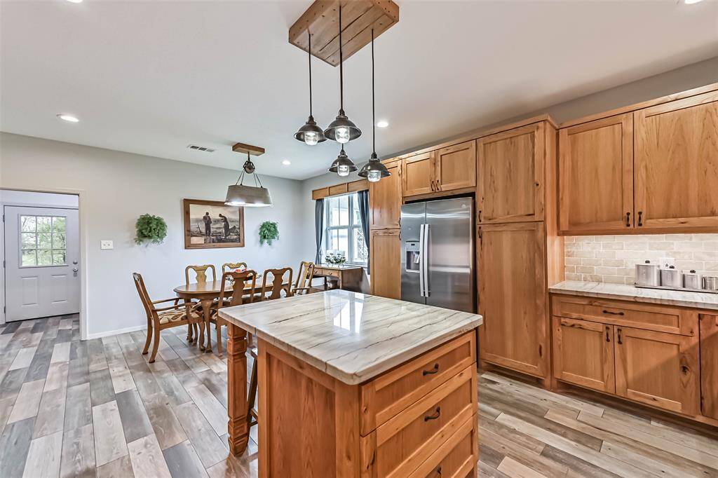 Chef's eat-in island kitchen features custom hickory cabinets, designer backsplash, lengthy countertops, stainless steel appliances and under cabinet lighting