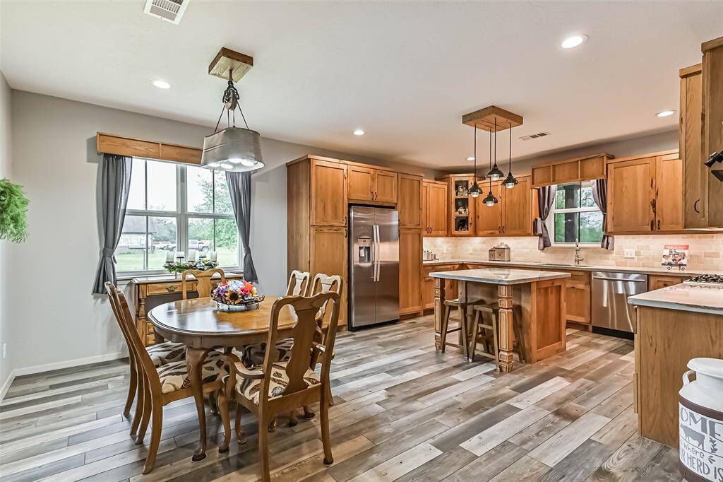 Chef's eat-in island kitchen features custom hickory cabinets, designer backsplash, lengthy quartz countertops, stainless steel appliances and under cabinet lighting