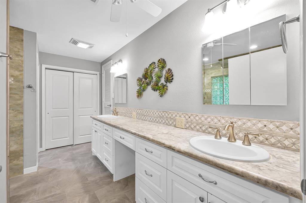 Primary bath with double vanity, seating area, and linen closet.