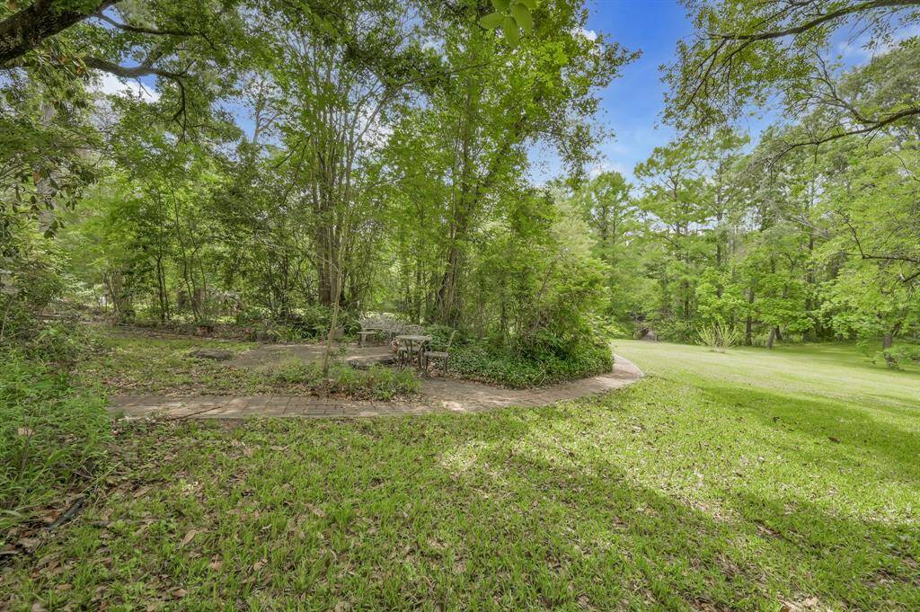 View from the back of the house looking toward the lake. Paved walk way, sitting area and small pond.