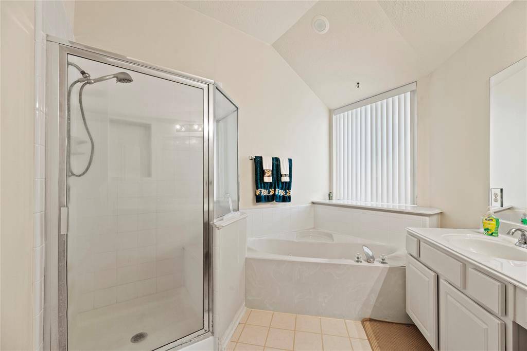 The primary bath features dual vanities, providing ample personal space along with an abundance of custom cabinetry for seamless organization.