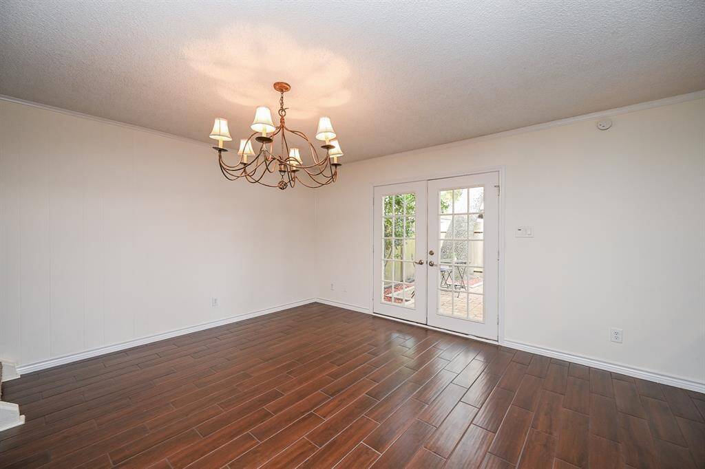 This room features hardwood flooring, a stylish chandelier, and French doors leading to a cozy outdoor patio, creating a bright and inviting space.