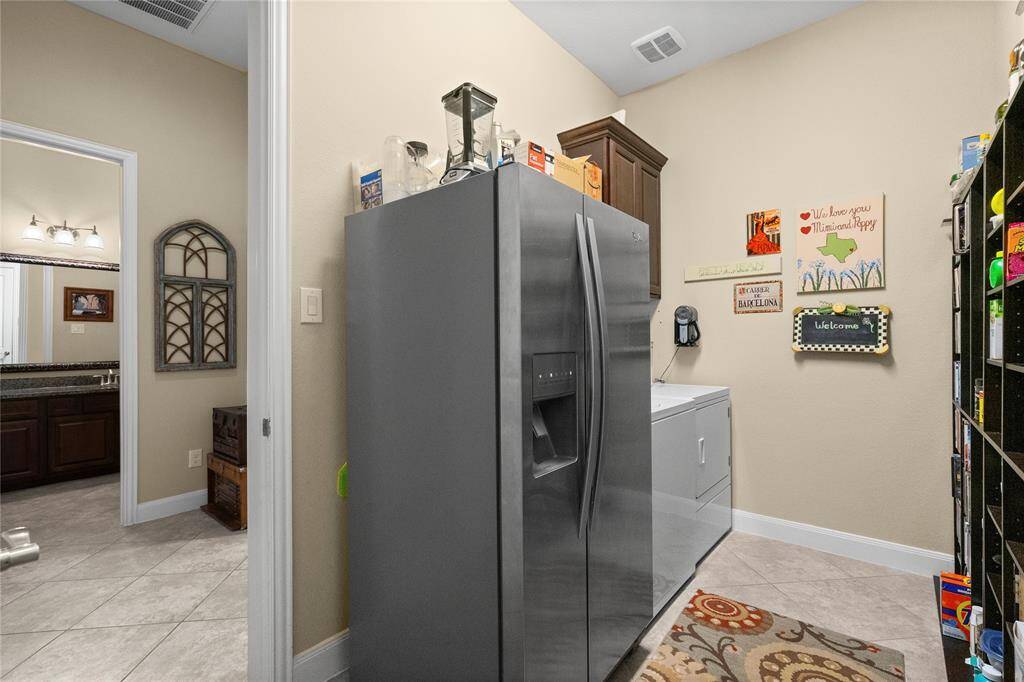This photo shows a cozy utility room with enough room for a stainless steel refrigerator and a washing machine.