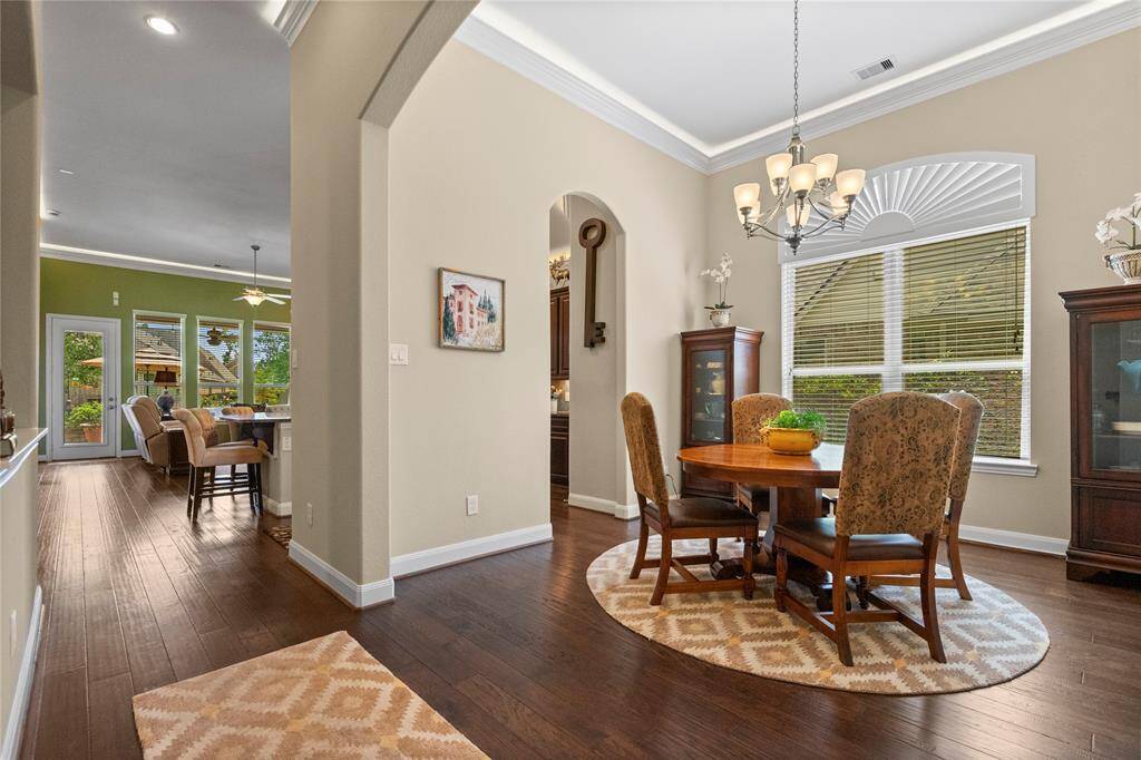 This photo showcases a warm, inviting dining area with wooden floors. The view extends to a bright, open kitchen and living space, enhancing the home's open-concept feel.