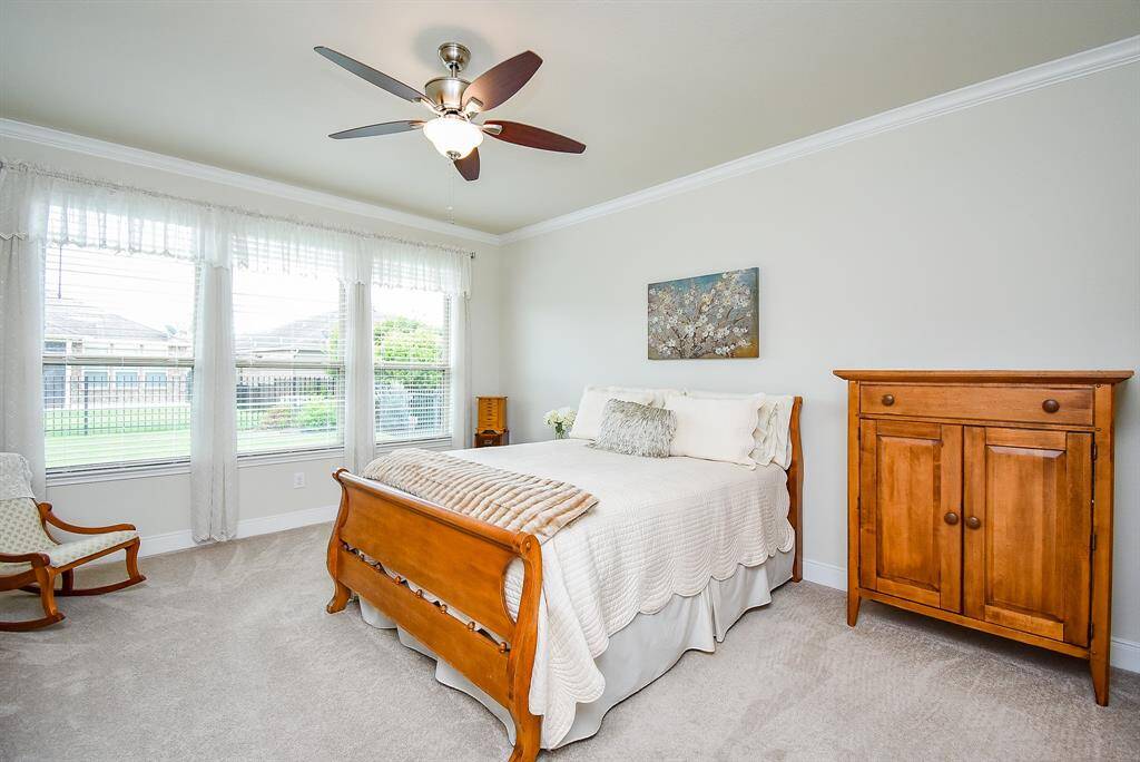 Welcome to your serene primary suite, featuring large picture windows that flood the room with natural light. The added ceiling fan ensures comfort, while the crown molding beautifully frames the ceilings, adding an elegant touch.