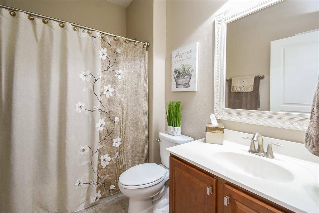 The full bathroom in the hallway features upgraded countertops, a stylish mirror, and modern light fixtures, adding a touch of elegance. While not shown in this picture, the room also includes a spacious floor to ceiling storage closet for added functionality.