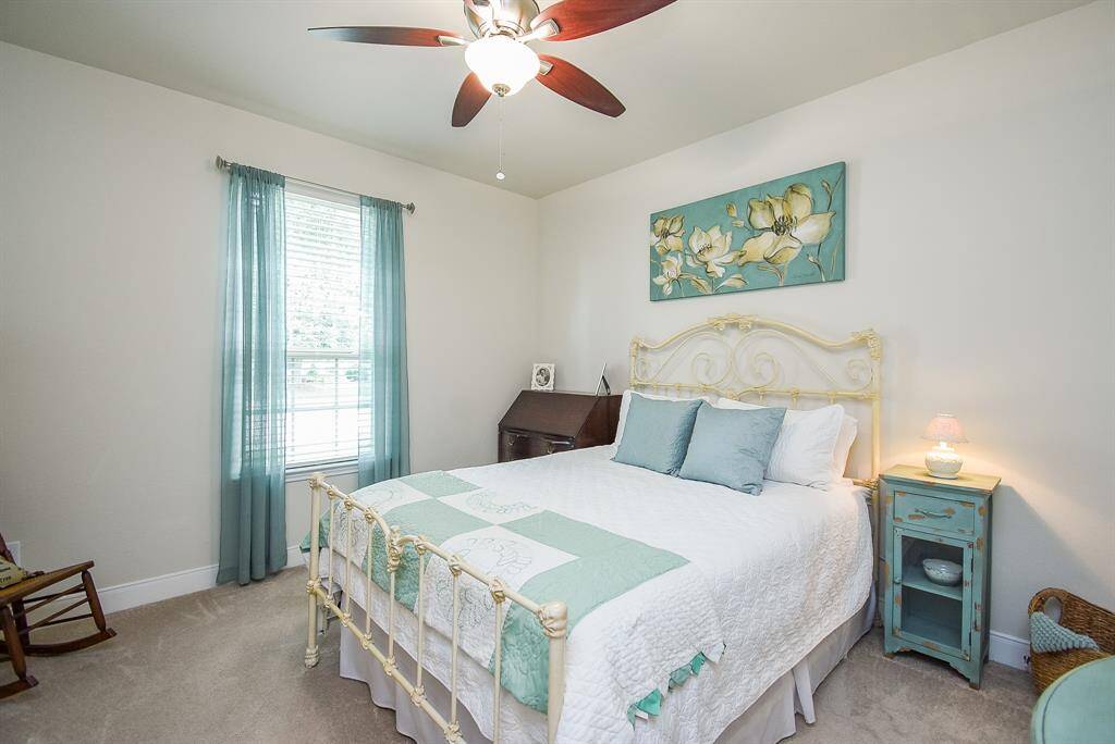 The secondary bedroom, located at the front of the home, features a large window that fills the space with natural light, an added ceiling fan for comfort, and a spacious walk-in closet offering ample storage.