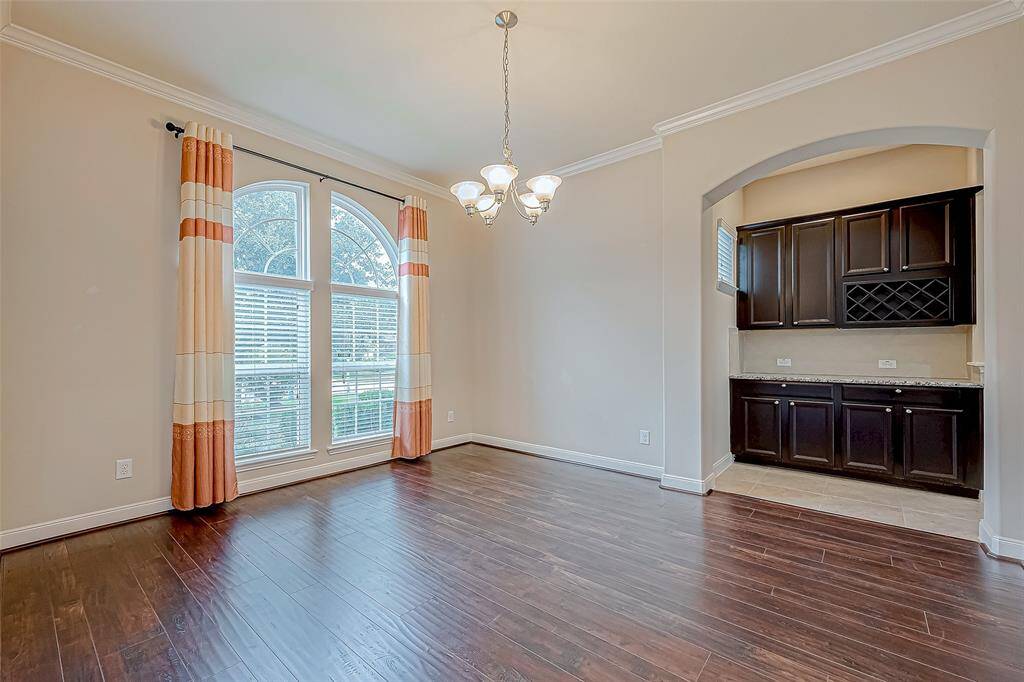 This formal dining area features elegant lighting and beautiful wood flooring, creating a warm and inviting space for gatherings. Entrance to the kitchen.