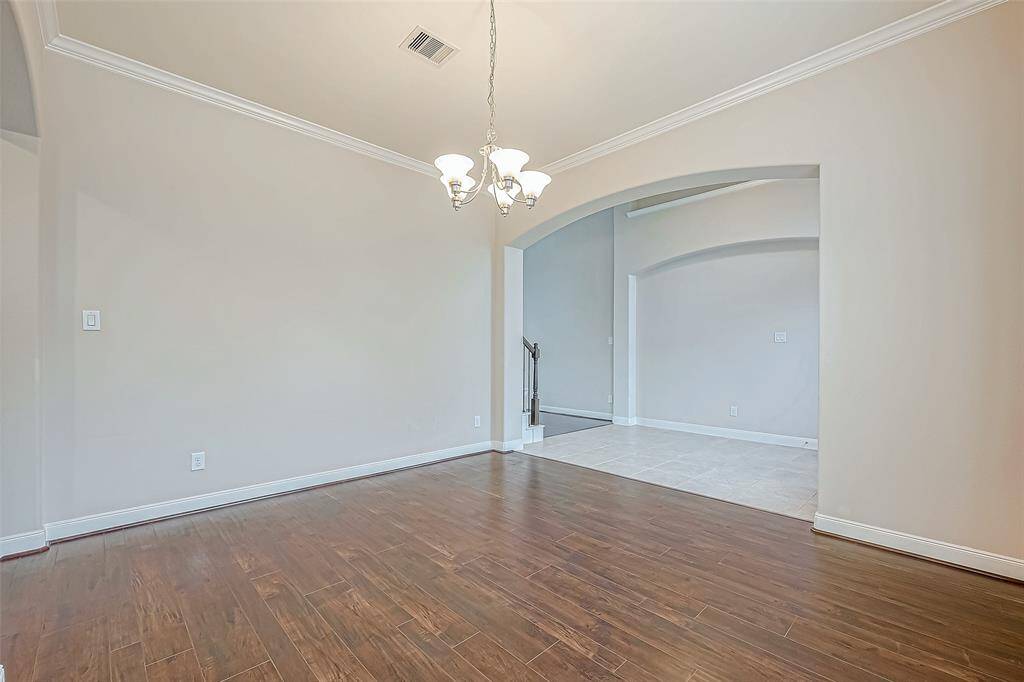 This formal dining area features elegant lighting and beautiful wood flooring, creating a warm and inviting space for gatherings. Entrance to the kitchen.