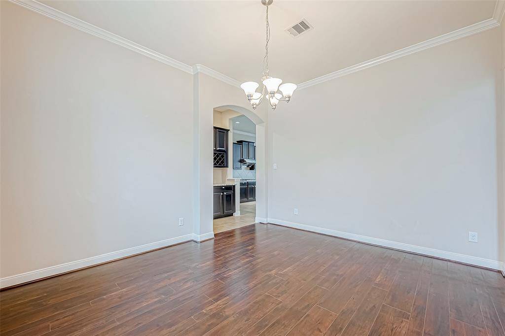 This formal dining area features elegant lighting and beautiful wood flooring, creating a warm and inviting space for gatherings. Entrance to the kitchen.